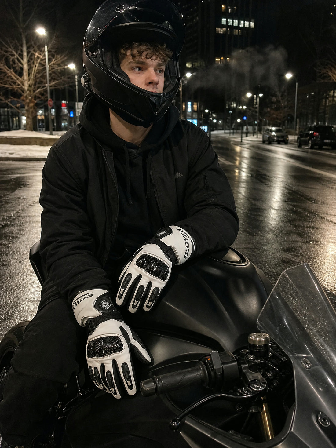 Rider on a black sportbike at night wearing the carbon heated gloves