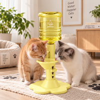 Two cats drinking from the yellow dispenser View 10