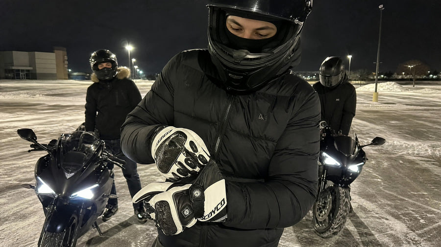 Young riders with sportbikes in a snowy parking lot at night, one tightening the cuff of a carbon heated glove